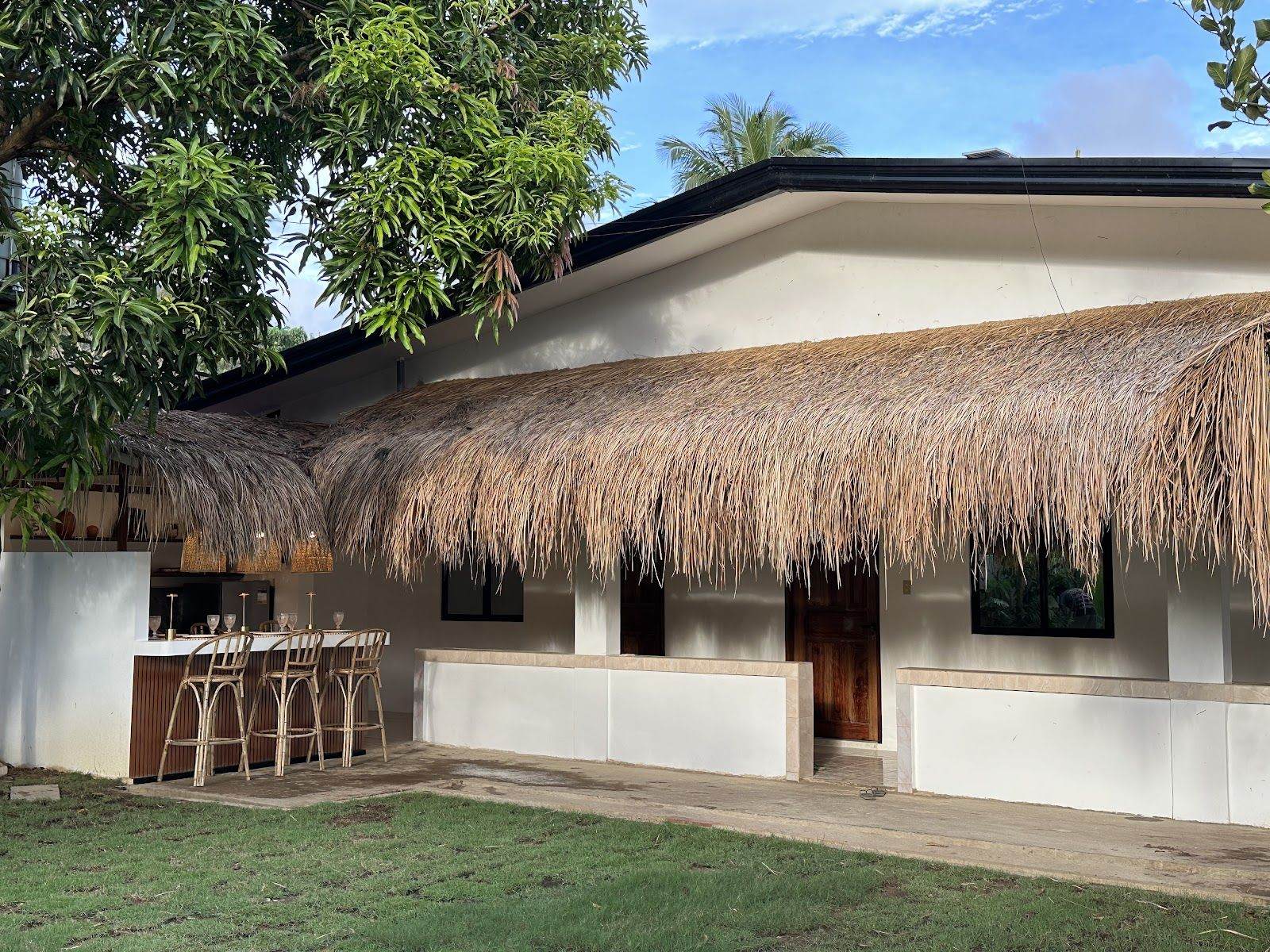 Villa Aniani: a thatched roof and white walls across the lawn