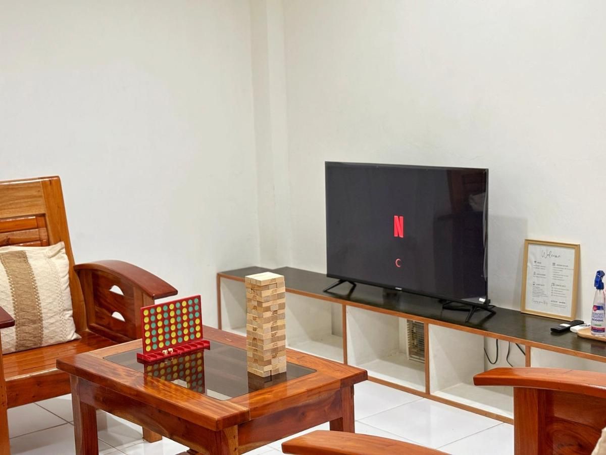 Living room with wooden armchairs, a TV and board games