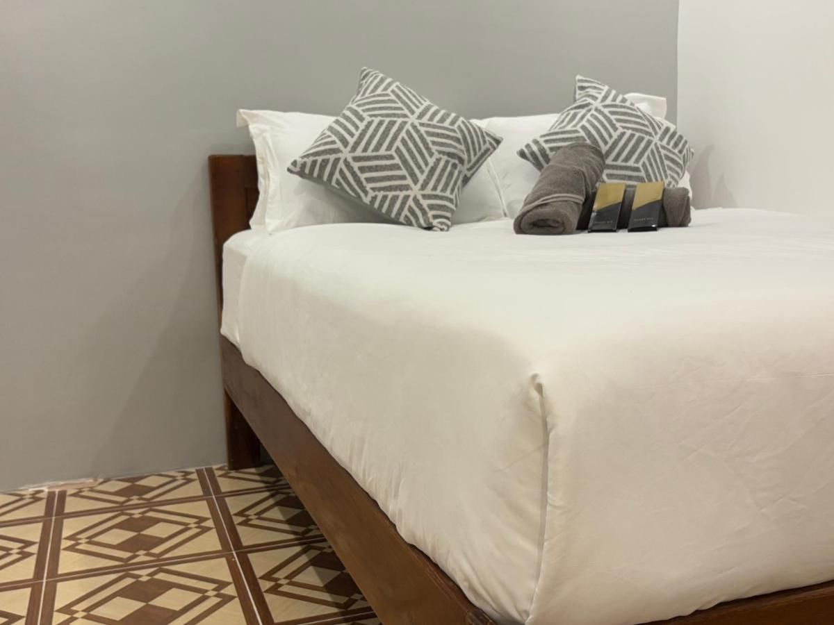 Double bed with patterned cushions on a tiled floor