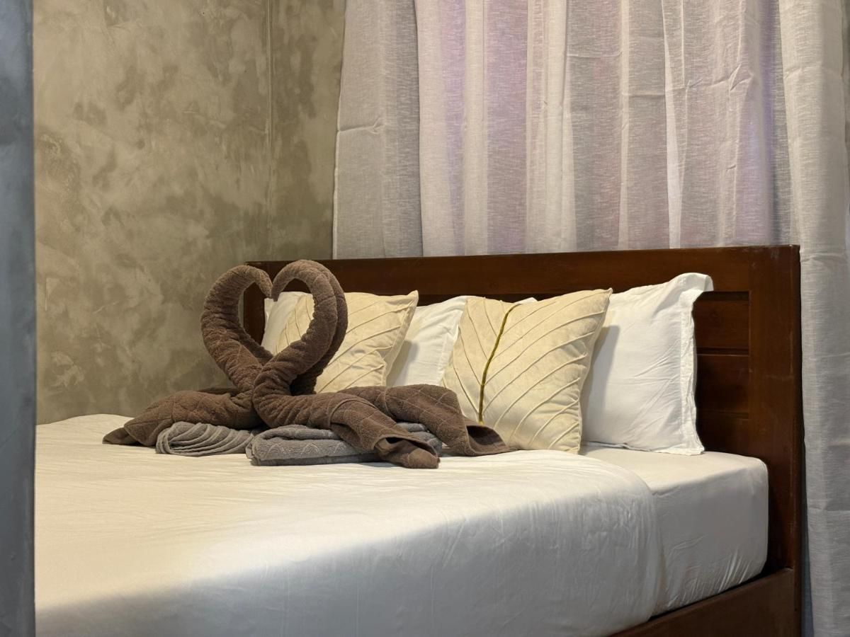 Queen bed with towel swans against a polished-concrete wall