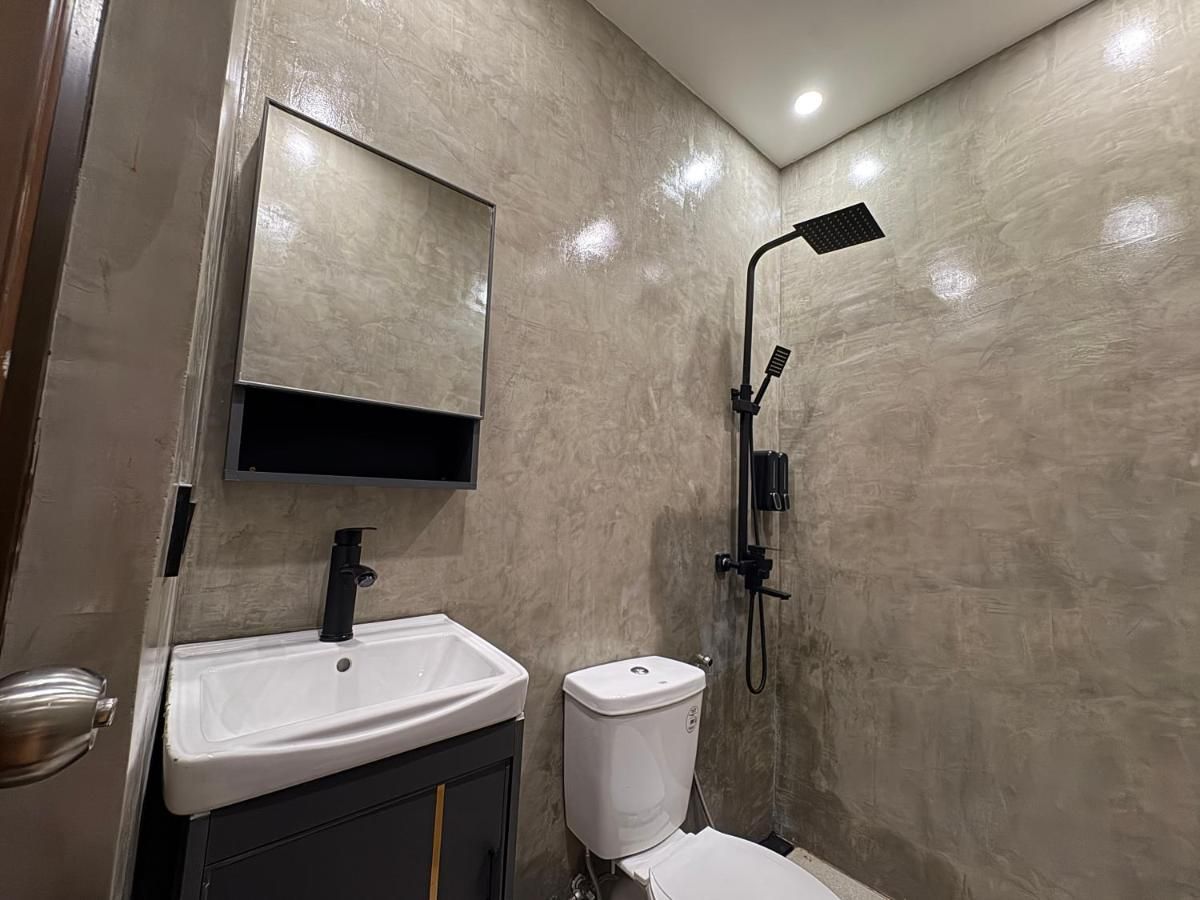 Bathroom with rain shower, basin and polished-concrete walls