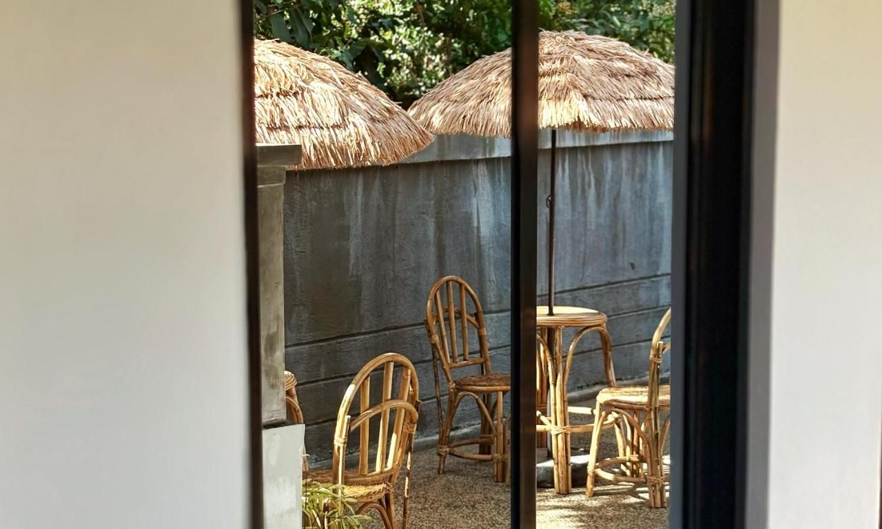 Rattan chairs and thatched umbrellas seen through a doorway