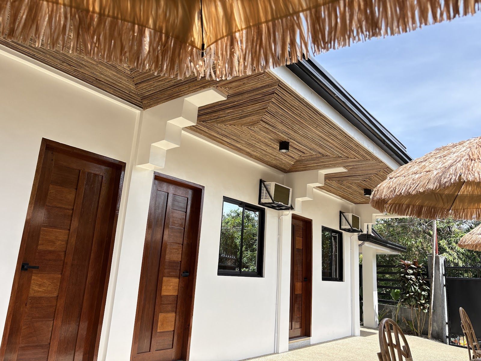 Solana Inn: a white building with hardwood doors and a thatched umbrella under a blue sky
